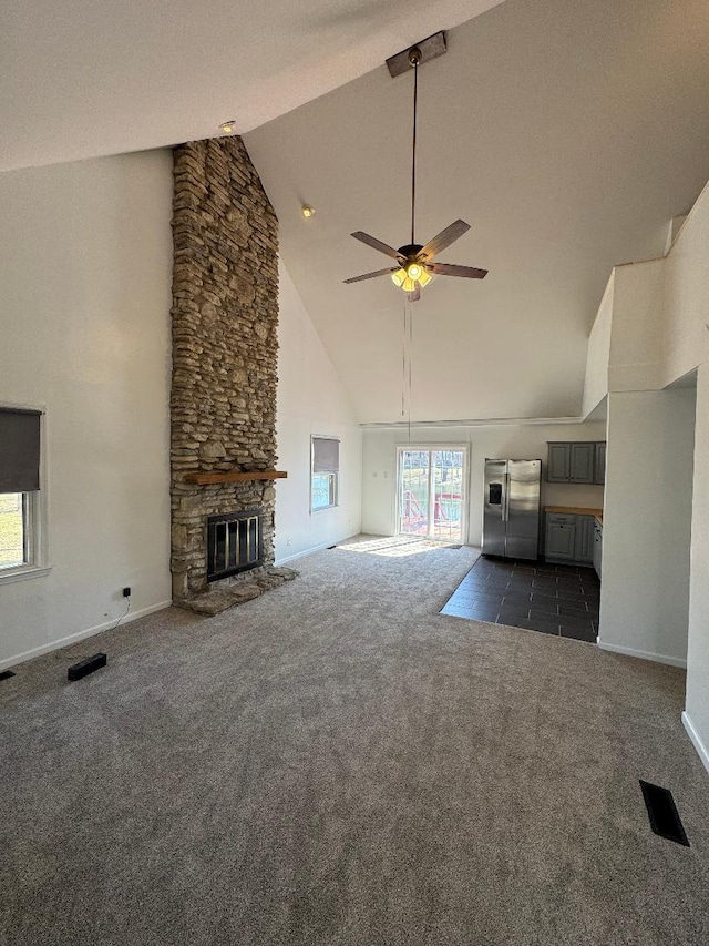 unfurnished living room with visible vents, a ceiling fan, a stone fireplace, and dark carpet