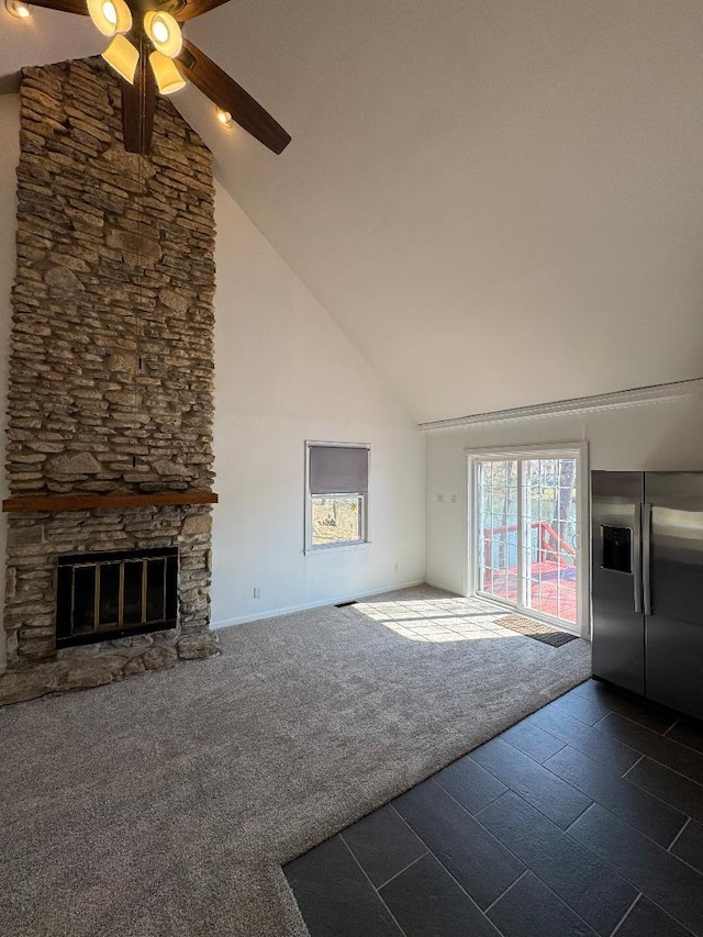 unfurnished living room with ceiling fan, a fireplace, dark colored carpet, and high vaulted ceiling