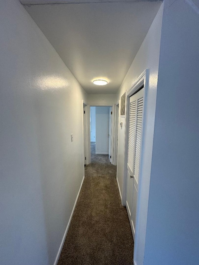 hallway featuring carpet flooring and baseboards