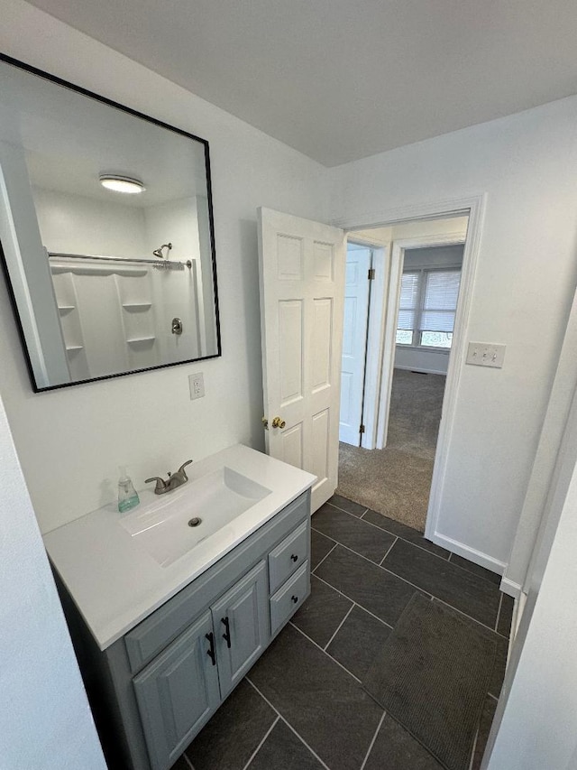 bathroom featuring vanity, tile patterned floors, baseboards, and walk in shower