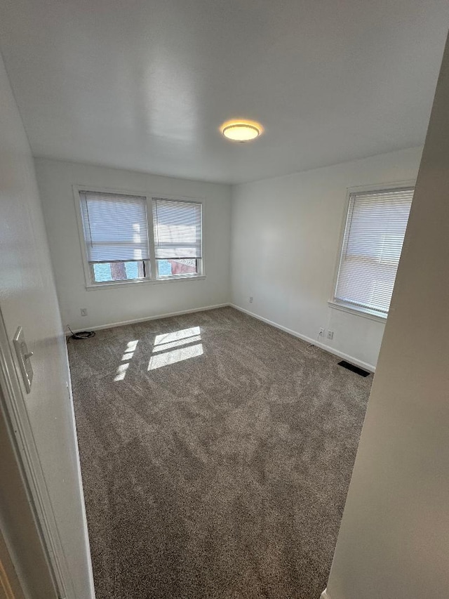 carpeted empty room featuring visible vents and baseboards