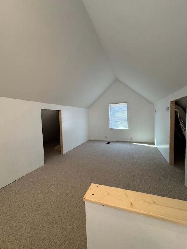 bonus room with vaulted ceiling and carpet floors