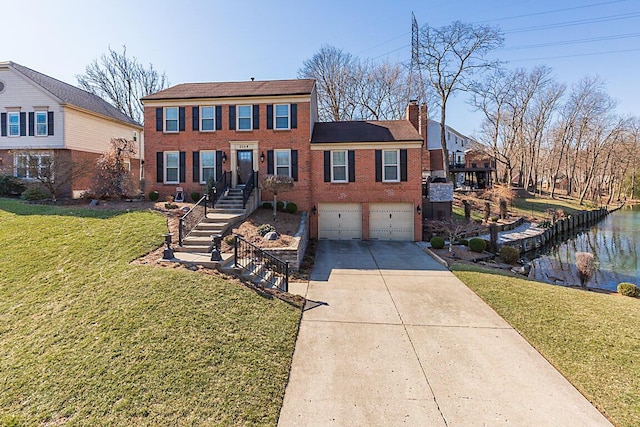 colonial inspired home with driveway, an attached garage, a chimney, a front lawn, and brick siding