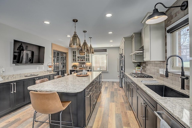 kitchen featuring a healthy amount of sunlight, a kitchen island, light wood-type flooring, and a sink