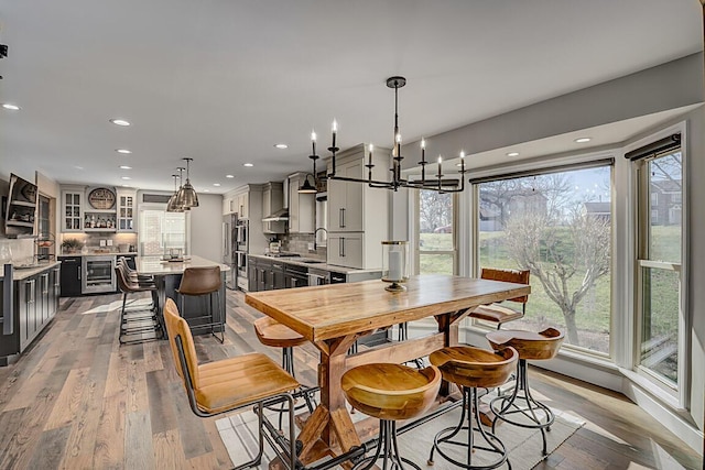 dining room with recessed lighting, wine cooler, light wood-style floors, and a healthy amount of sunlight