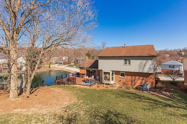 back of house with brick siding, a shingled roof, a yard, and a water view