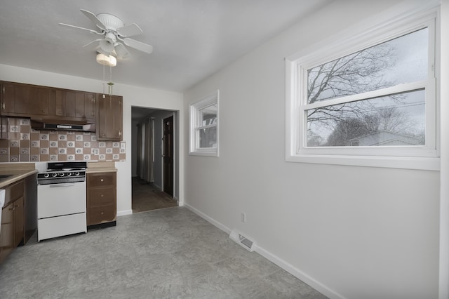 kitchen featuring under cabinet range hood, electric range, visible vents, light countertops, and backsplash