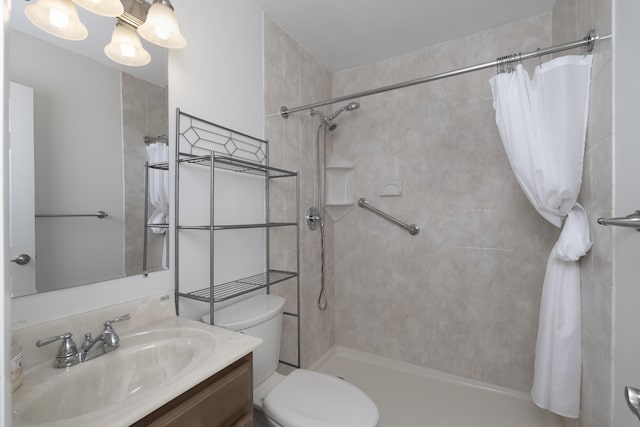 bathroom with toilet, tiled shower, a chandelier, and vanity