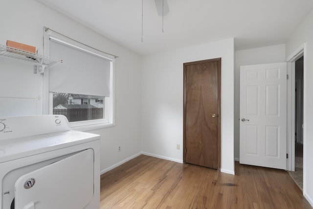 clothes washing area with washer / dryer, laundry area, light wood finished floors, baseboards, and a ceiling fan