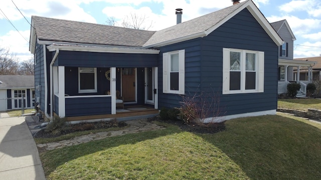 bungalow-style house with covered porch, a front lawn, and a shingled roof