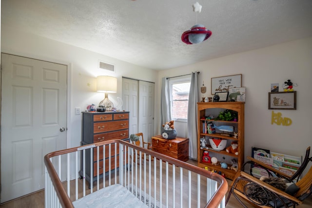 bedroom with visible vents, wood finished floors, a closet, and a textured ceiling