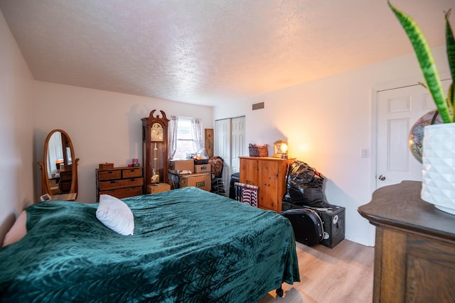 bedroom featuring visible vents, baseboards, light wood-style flooring, a closet, and a textured ceiling