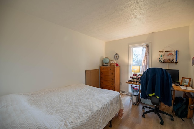 bedroom with a textured ceiling and wood finished floors