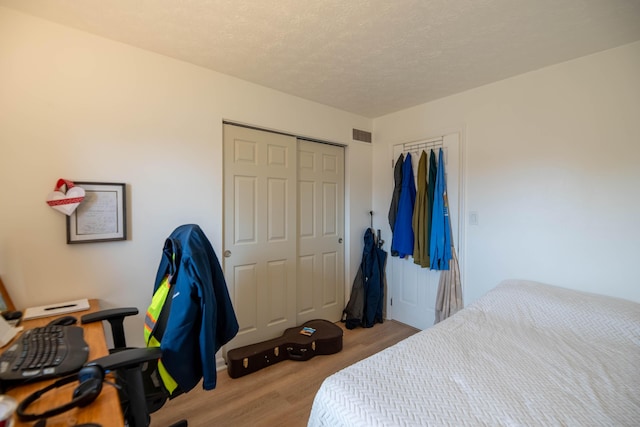 bedroom featuring visible vents, light wood-style floors, a closet, and a textured ceiling