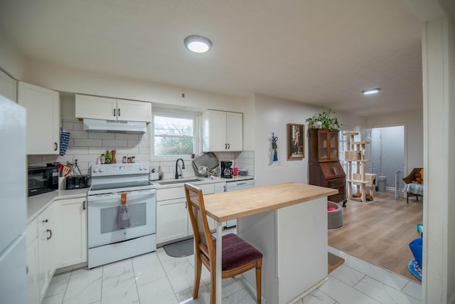 kitchen with marble finish floor, under cabinet range hood, a sink, white appliances, and decorative backsplash