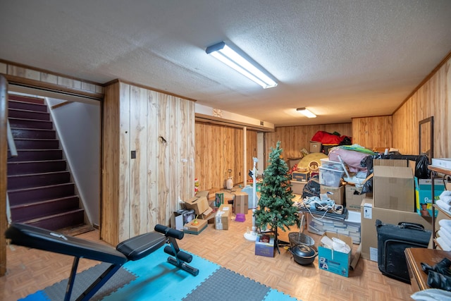 finished below grade area featuring stairway, wooden walls, and a textured ceiling