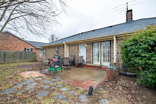 back of property featuring fence, french doors, brick siding, a chimney, and a patio area