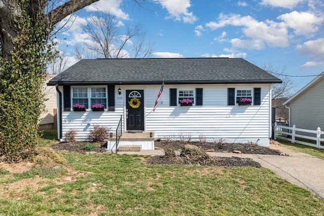 ranch-style house featuring a shingled roof, a front lawn, and fence