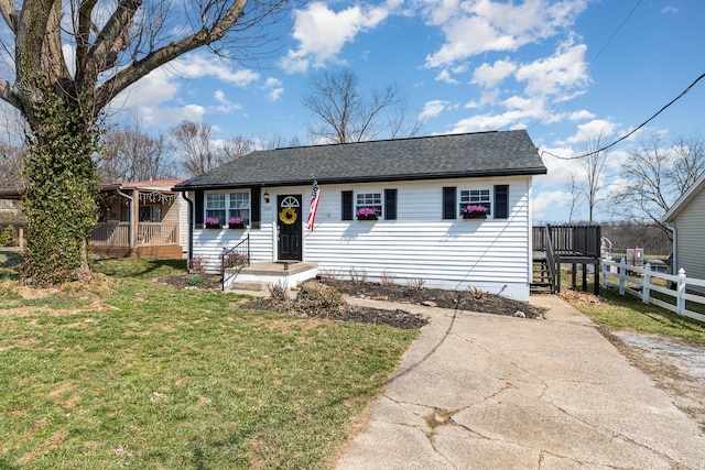 ranch-style house with roof with shingles, a front lawn, and fence