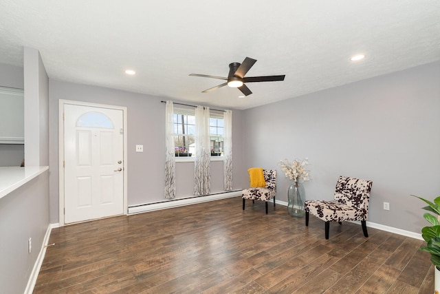 living area featuring wood finished floors, baseboards, baseboard heating, and ceiling fan