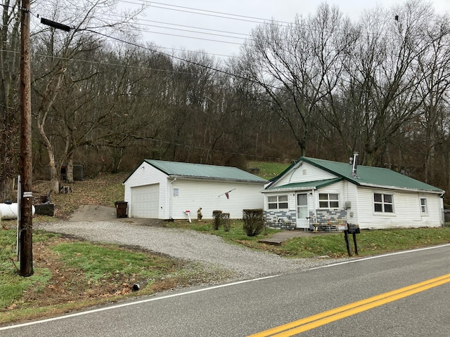 view of front of property with driveway, entry steps, metal roof, and an outbuilding