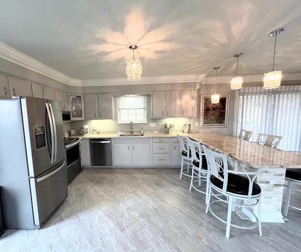 kitchen featuring light stone counters, stainless steel appliances, a breakfast bar, a peninsula, and a sink