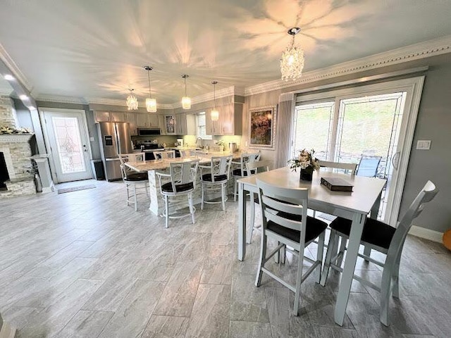 dining space with plenty of natural light, a fireplace, baseboards, and crown molding