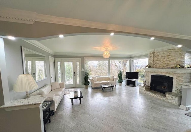 living room featuring a stone fireplace and crown molding