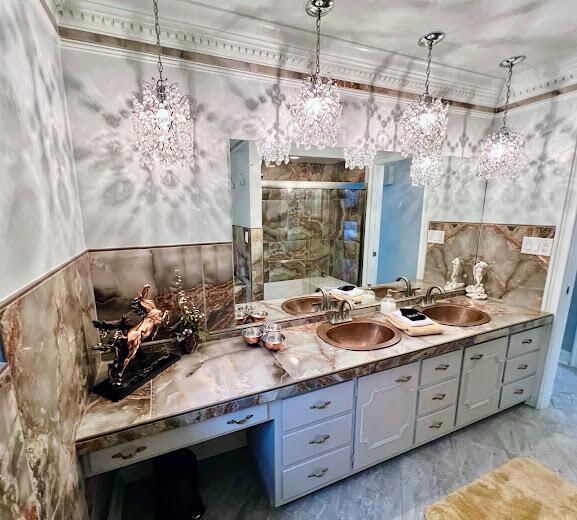 full bathroom featuring double vanity, a sink, tile walls, and crown molding