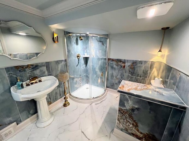 full bath featuring a sink, tile walls, marble finish floor, wainscoting, and a shower stall