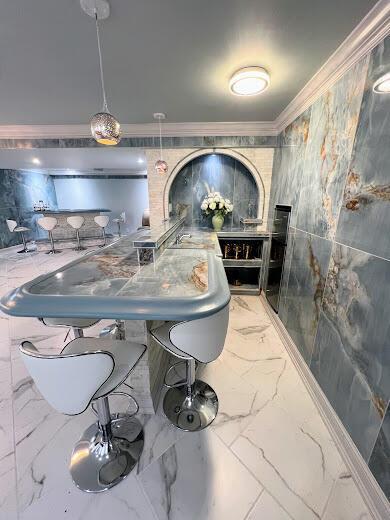 bar with marble finish floor and crown molding