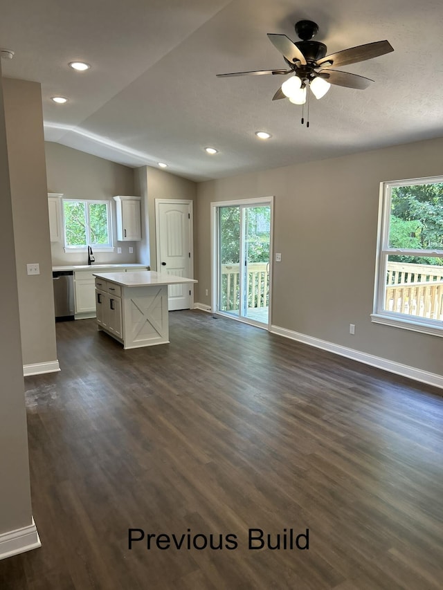 interior space featuring lofted ceiling, open floor plan, white cabinetry, a kitchen island, and dishwasher