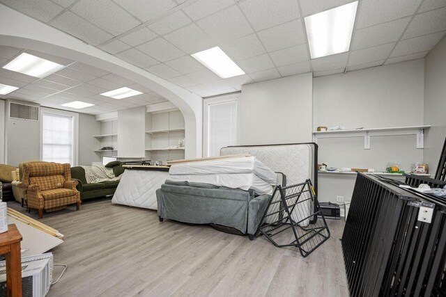 bedroom featuring a paneled ceiling, visible vents, arched walkways, and light wood finished floors