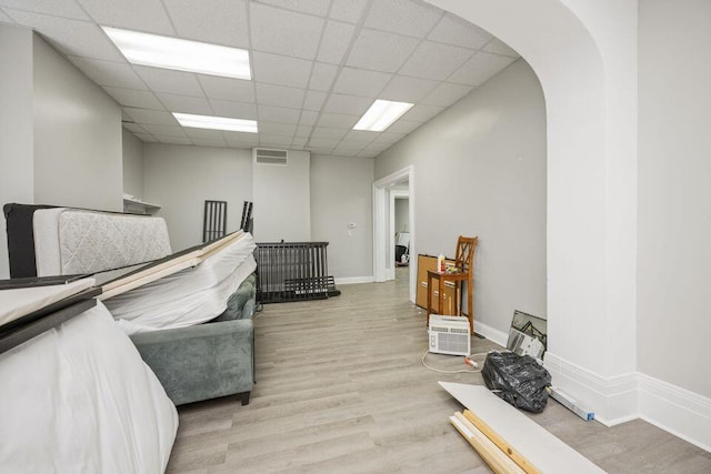 miscellaneous room with visible vents, arched walkways, baseboards, light wood-style flooring, and a paneled ceiling