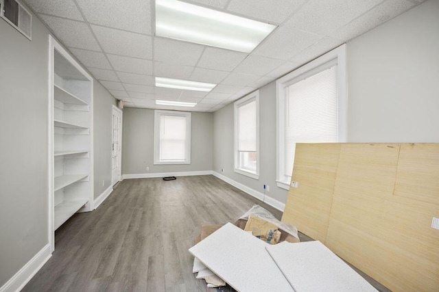 spare room featuring visible vents, a drop ceiling, baseboards, and wood finished floors