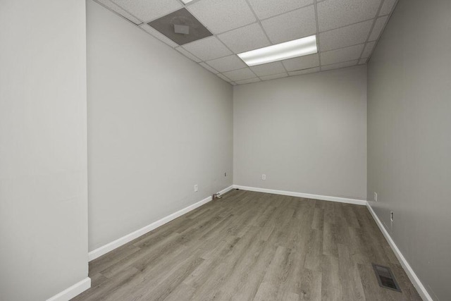 unfurnished room featuring a drop ceiling, wood finished floors, visible vents, and baseboards