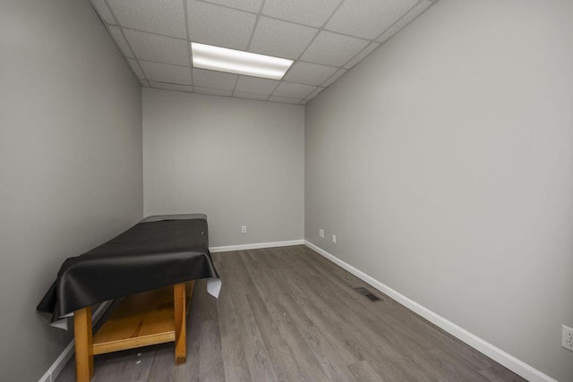 interior space with a drop ceiling, wood finished floors, visible vents, and baseboards