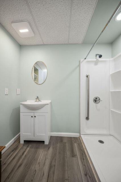 bathroom featuring a shower, wood finished floors, vanity, and baseboards