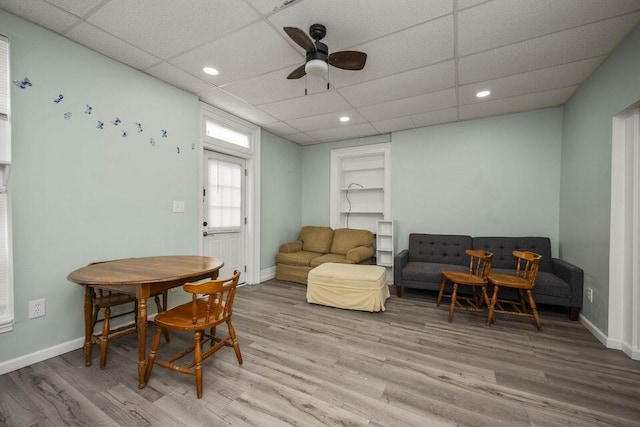 living room with a paneled ceiling, a ceiling fan, baseboards, and wood finished floors