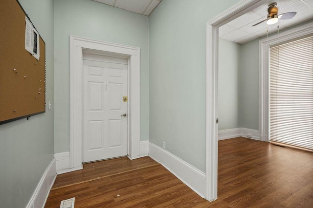 hall with a paneled ceiling, visible vents, baseboards, and wood finished floors