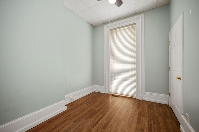 unfurnished room with ceiling fan, wood finished floors, a paneled ceiling, and baseboards