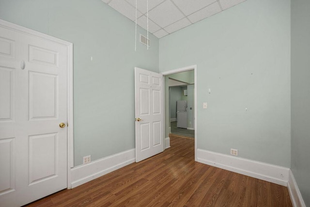 unfurnished room featuring a paneled ceiling, dark wood-style flooring, visible vents, and baseboards