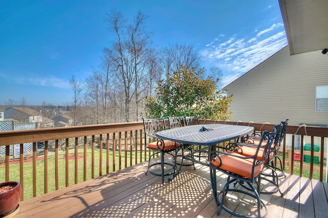 wooden deck featuring outdoor dining area and a lawn