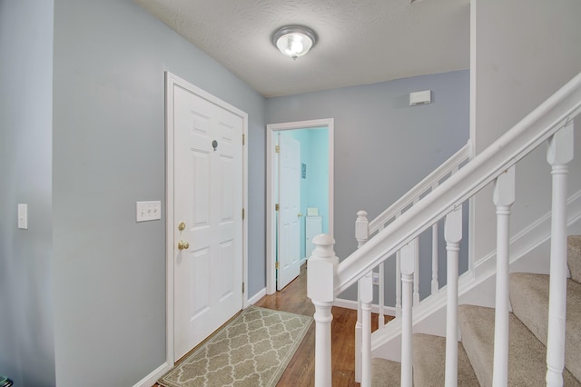 foyer entrance featuring baseboards, wood finished floors, and stairs