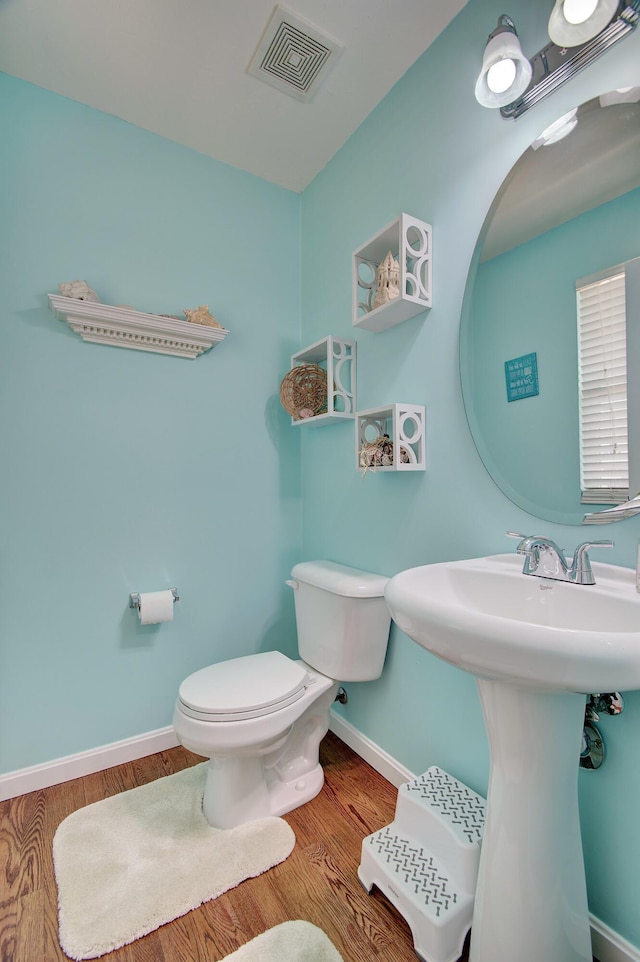 bathroom featuring wood finished floors, visible vents, baseboards, a sink, and toilet