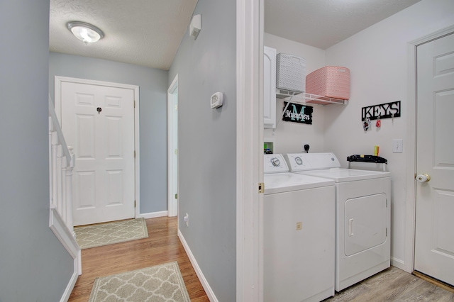 laundry area with laundry area, washer and dryer, light wood-style flooring, and baseboards