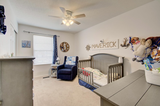 carpeted bedroom with a textured ceiling, baseboards, and ceiling fan