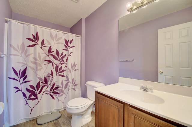 bathroom with toilet, a textured ceiling, wood finished floors, a shower with shower curtain, and vanity