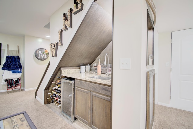 bar with a sink, baseboards, light colored carpet, and beverage cooler