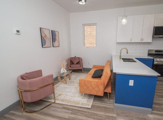 interior space featuring white cabinets, appliances with stainless steel finishes, a sink, light countertops, and backsplash